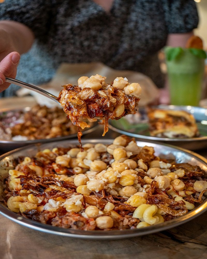 Traditional Egyptian Koshary street food dish with crispy onions and tomato sauce